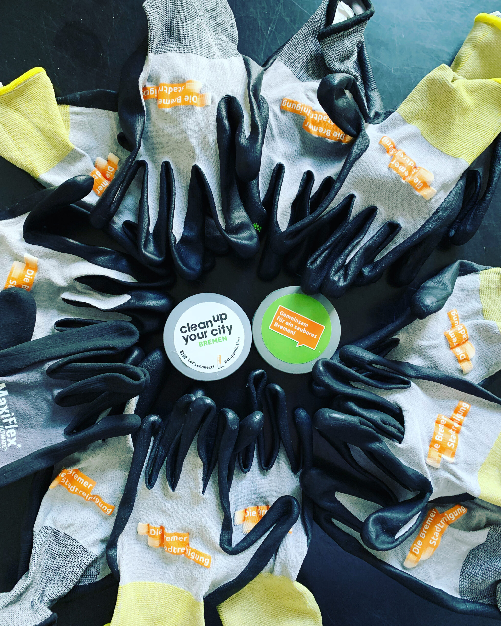 Zwei Taschenascher umzingelt von Gummihandschuhen mit dem Logo der Bremer Stadtreinigung